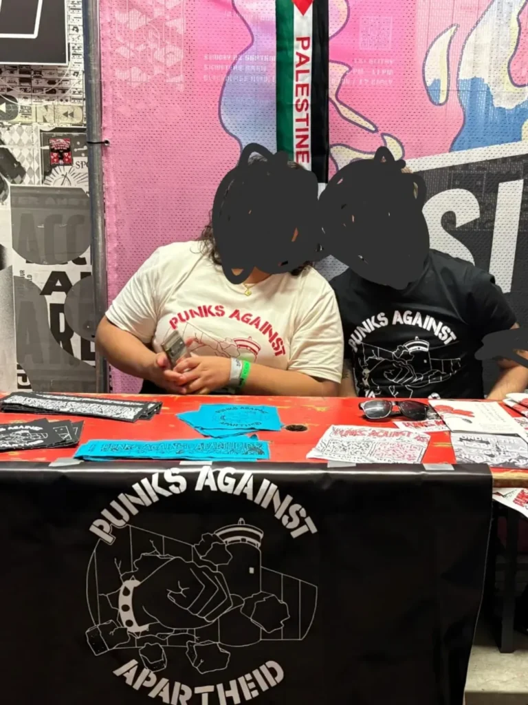Slide 11: A picture of two people wearing PAA t-shirts with a large PAA banner and merch on the table with their faces blotted out.