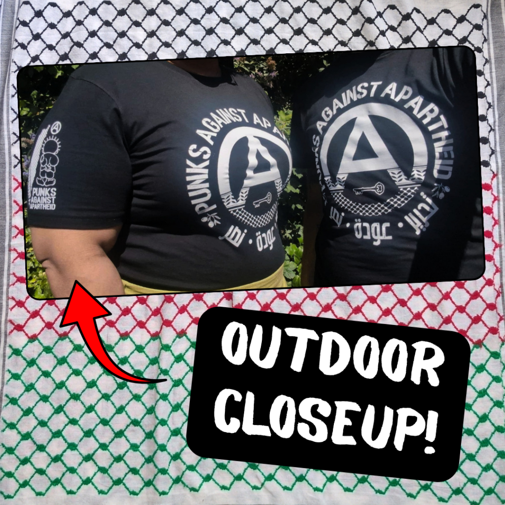 A picture of two people standing outside in front of trees showing the front and sleeve details:

A black t-shirt with a large circle (A) in the middle which fades into a keffiyyeh pattern towards the bottom. There is the silhouette of a key in the negative space at the bottom of the (A). The words PUNKS AGAINST APARTHEID ring the edge of the circle on top. On the bottom, two olive bunches on either side flank the words تجرير عودة نصر in Arabic. On the upper right sleeve (left to the viewer) there is a small map of Palestine with a keffiyyeh pattern overlaid, and a small cartoon Handhala figure, as well as a small circle (A). There is another picture of an even closer shot of the sleeve-detail and in the lower-right, 'OUTDOOR CLOSEUPS!' with arrows pointing to the images.