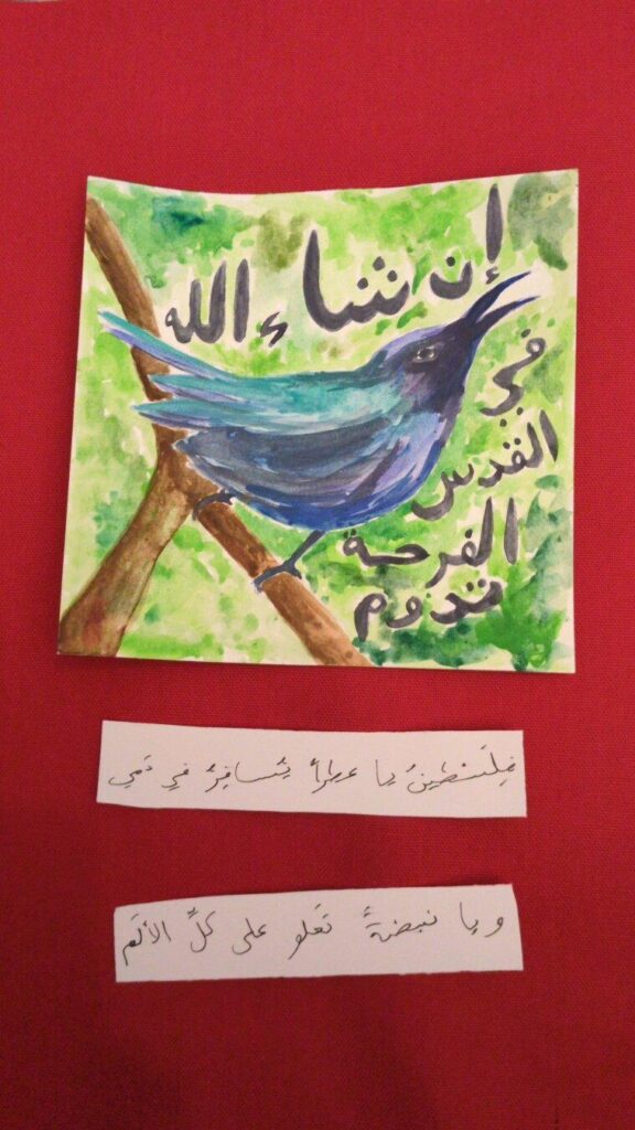 The drawing depicts a blue Gaza Sunbird perched on a brown branch against a green forest background and the phrase "إن شاء الله في القدس الفرحة تدوم", which means "God willing, joy will spread in Jerusalem." The poetic lines below read: "فِلَسْطينُ يا عِطراً يُسافِرُ في دَمي / ويا نبضةً تَعلو على كلِّ الألَم", which (artistically translated) means "O Palestine, you fragrant scent coursing through my veins / O beating pulse that transcends all pain." Set against a red background.